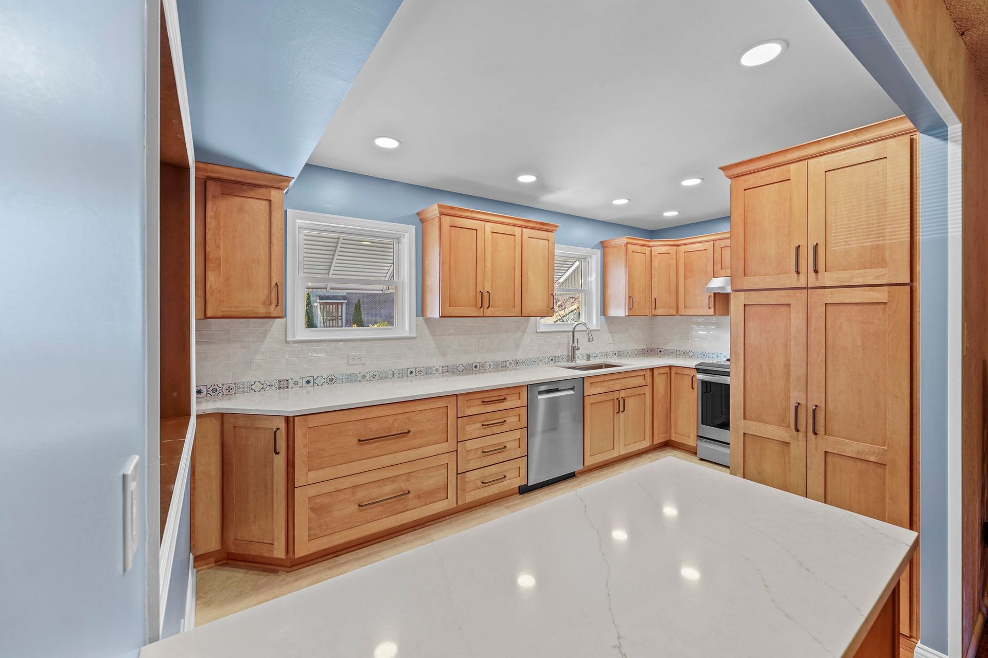 Bright modern kitchen with wooden cabinets, granite countertops, and tiled backsplash In Bucks County PA