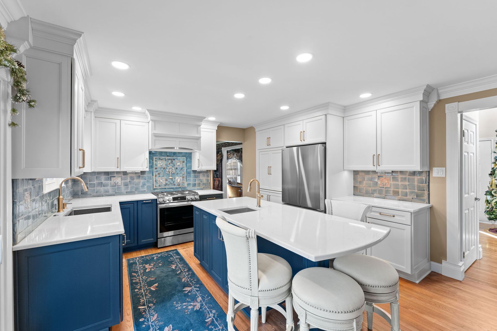 Bright kitchen with white cabinets, blue island, stainless fridge, and marble dining table  In Bucks County PA