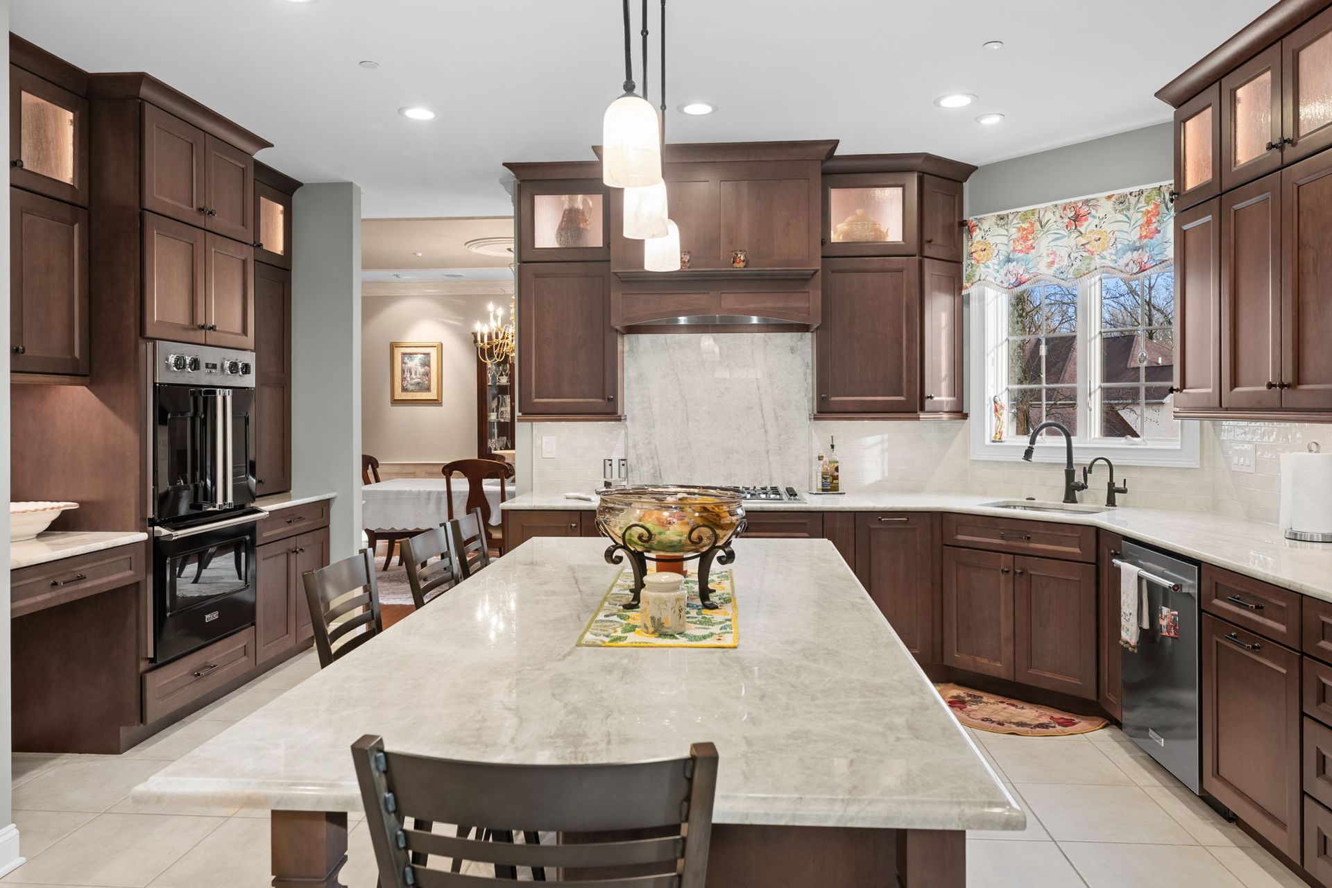 Modern kitchen with large island, dark wood cabinets, white countertops, and pendant lights In Bucks Country PA