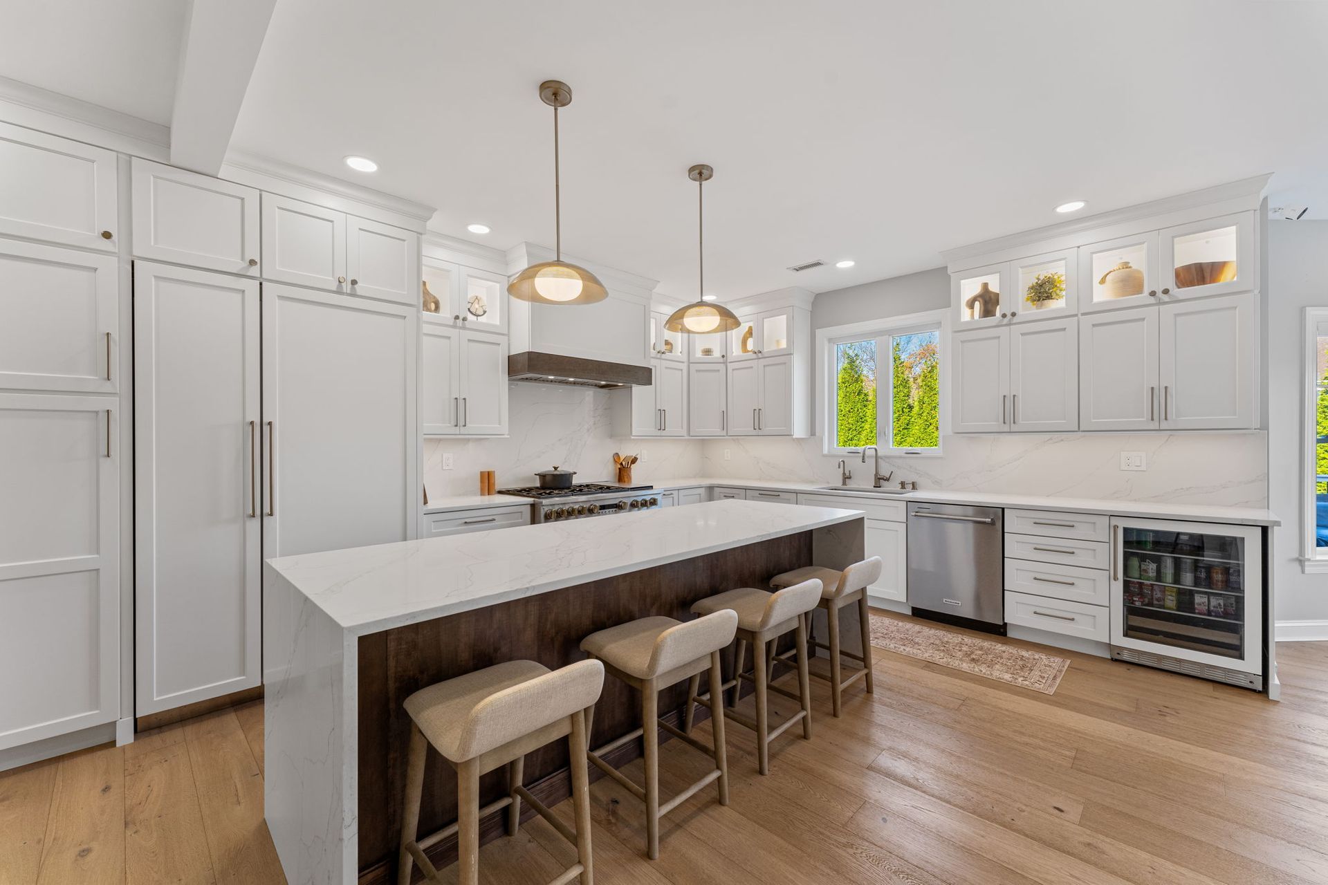 Bright modern kitchen with white cabinets, large island, bar stools, and wood floors In Bucks Country PA