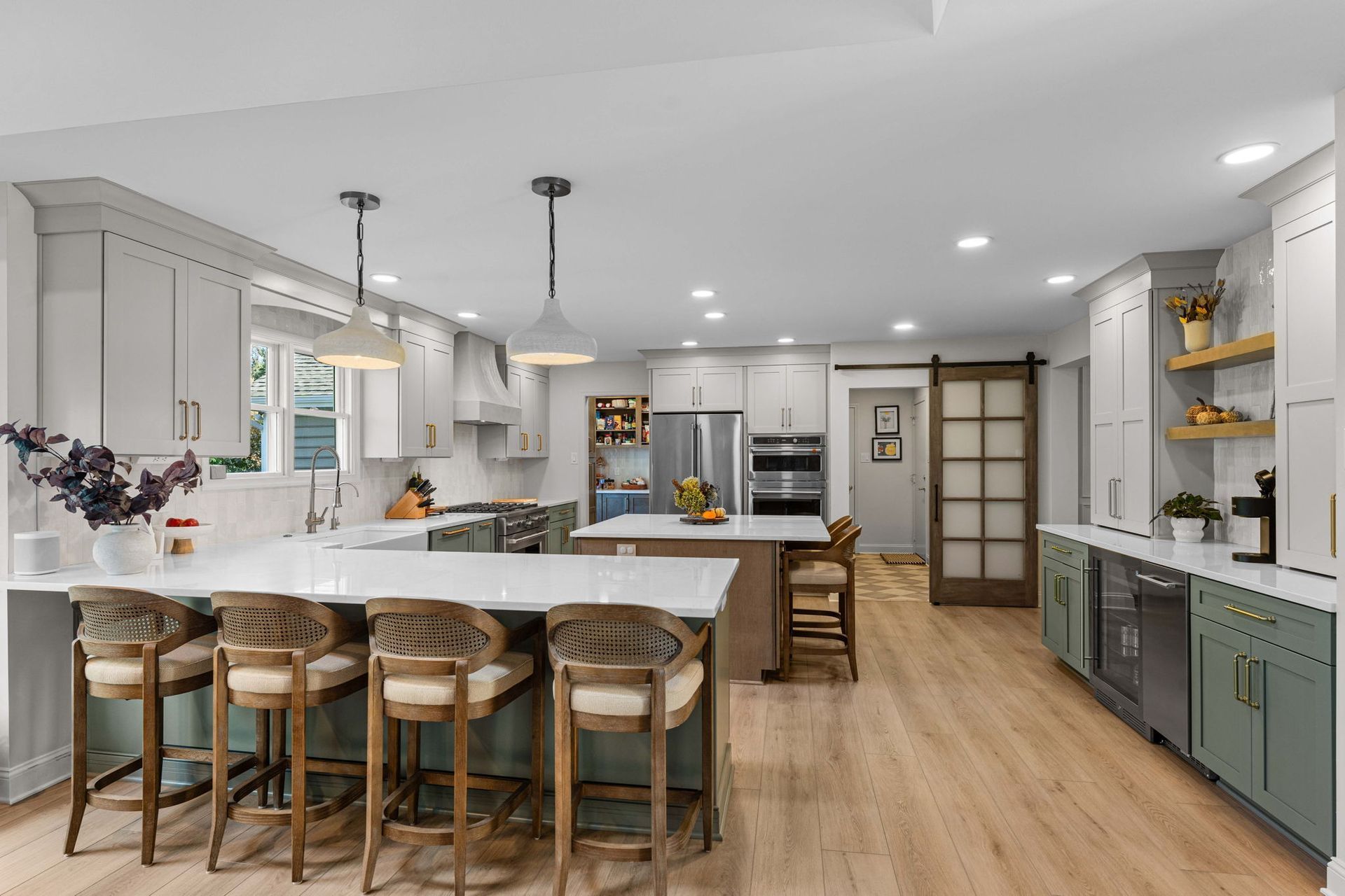 Bright modern kitchen with island, barstools, white cabinets, wood floors, and open shelving in Bucks Country PA
