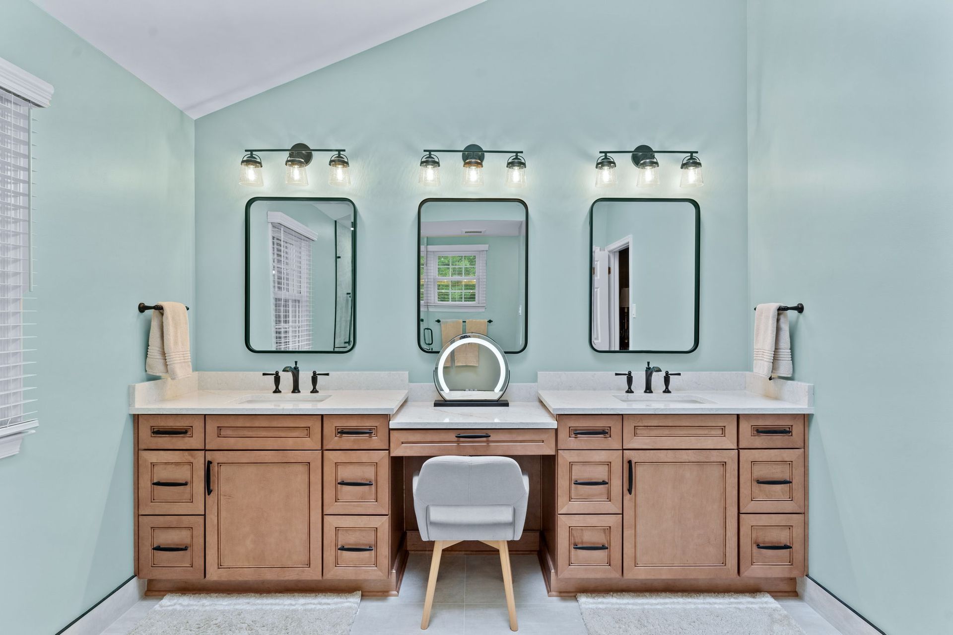 Modern bathroom vanity with three mirrors, wood cabinets, and pale blue walls  In Bucks County PA