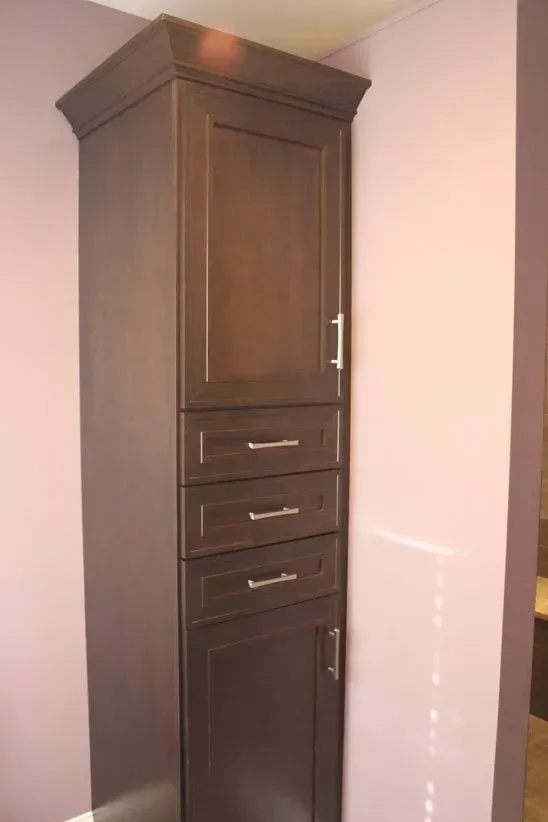 Tall dark wood cabinet with drawers and doors in a corner against light walls in Bucks Country PA