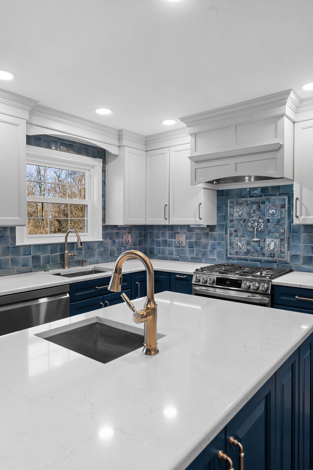 Bright modern kitchen with white cabinets, blue backsplash, and a white island with gold faucet  In Bucks County PA