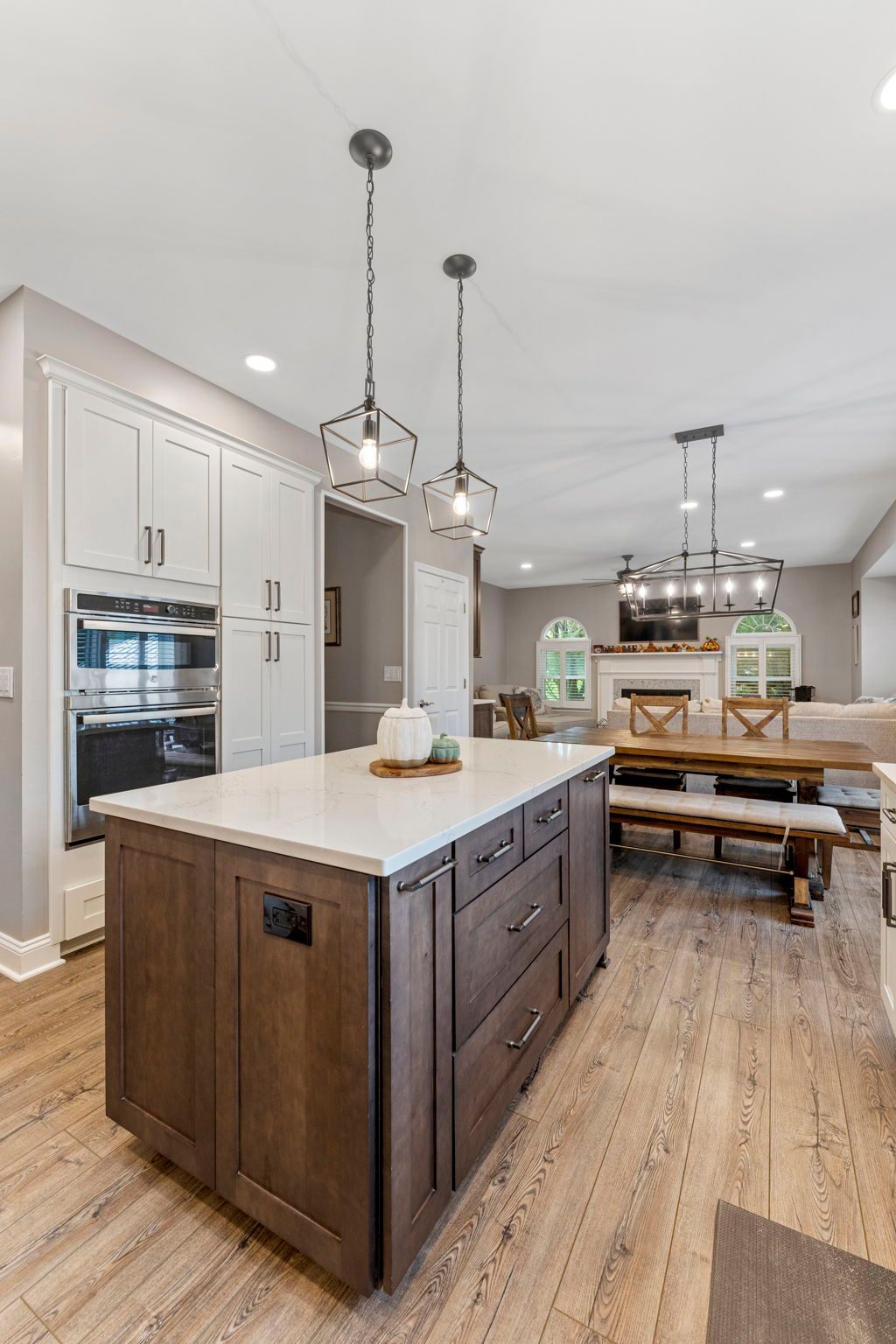 Bright modern kitchen with white cabinets, dark island, pendant lights, and wood dining table  In Bucks County PA