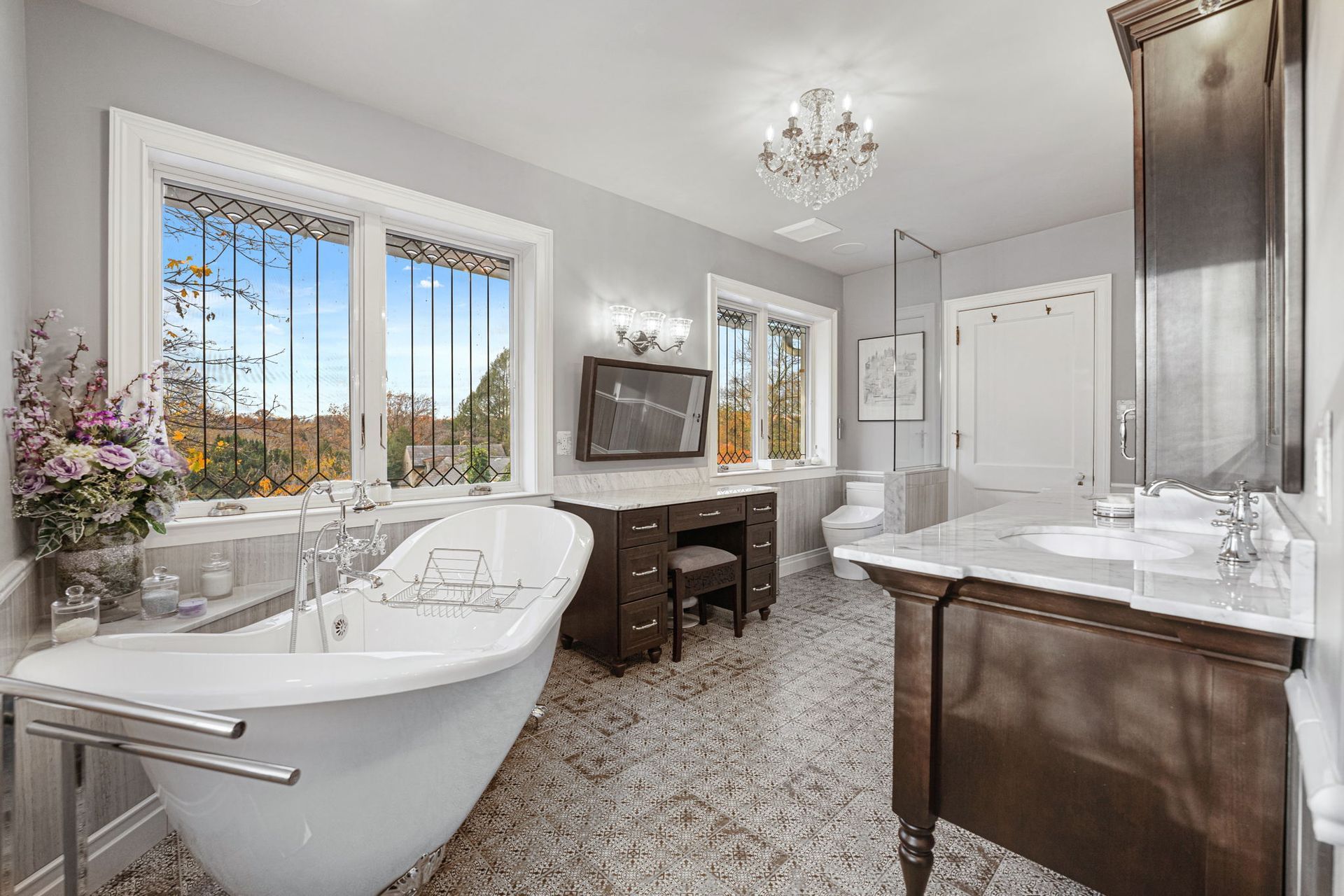 Bright modern bathroom with freestanding tub, double vanity, large windows, and marble finishes  In Bucks County PA