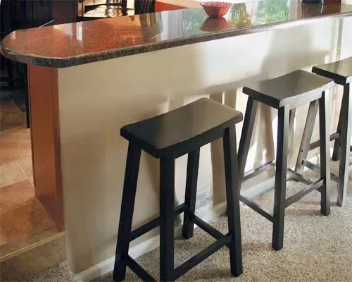 Three black bar stools beside a marble-topped kitchen island In Bucks County PA