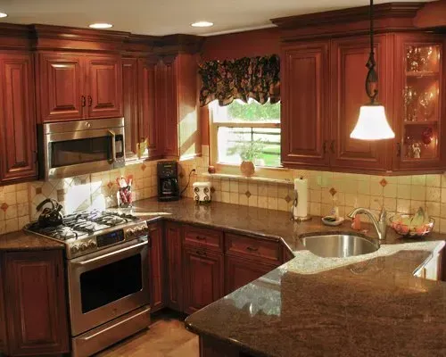 Warm kitchen with dark wood cabinets, granite counters, stainless appliances, and a window over the sink In Bucks Country PA