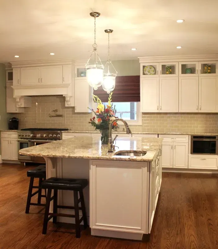 Bright kitchen with white cabinets, island, hanging lights, and hardwood floors In Bucks County PA