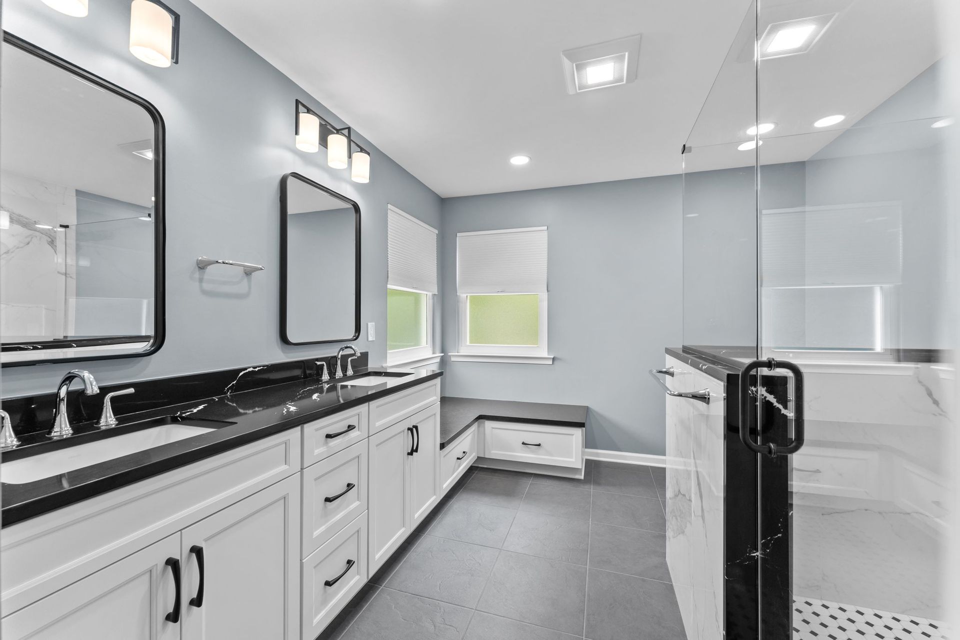 Bright modern bathroom with double vanity, large mirror, and glass shower enclosure In Bucks County PA