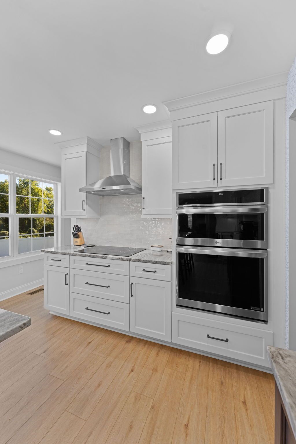 Bright modern white kitchen with stainless steel appliances, wood floor, and window light  In Bucks County PA