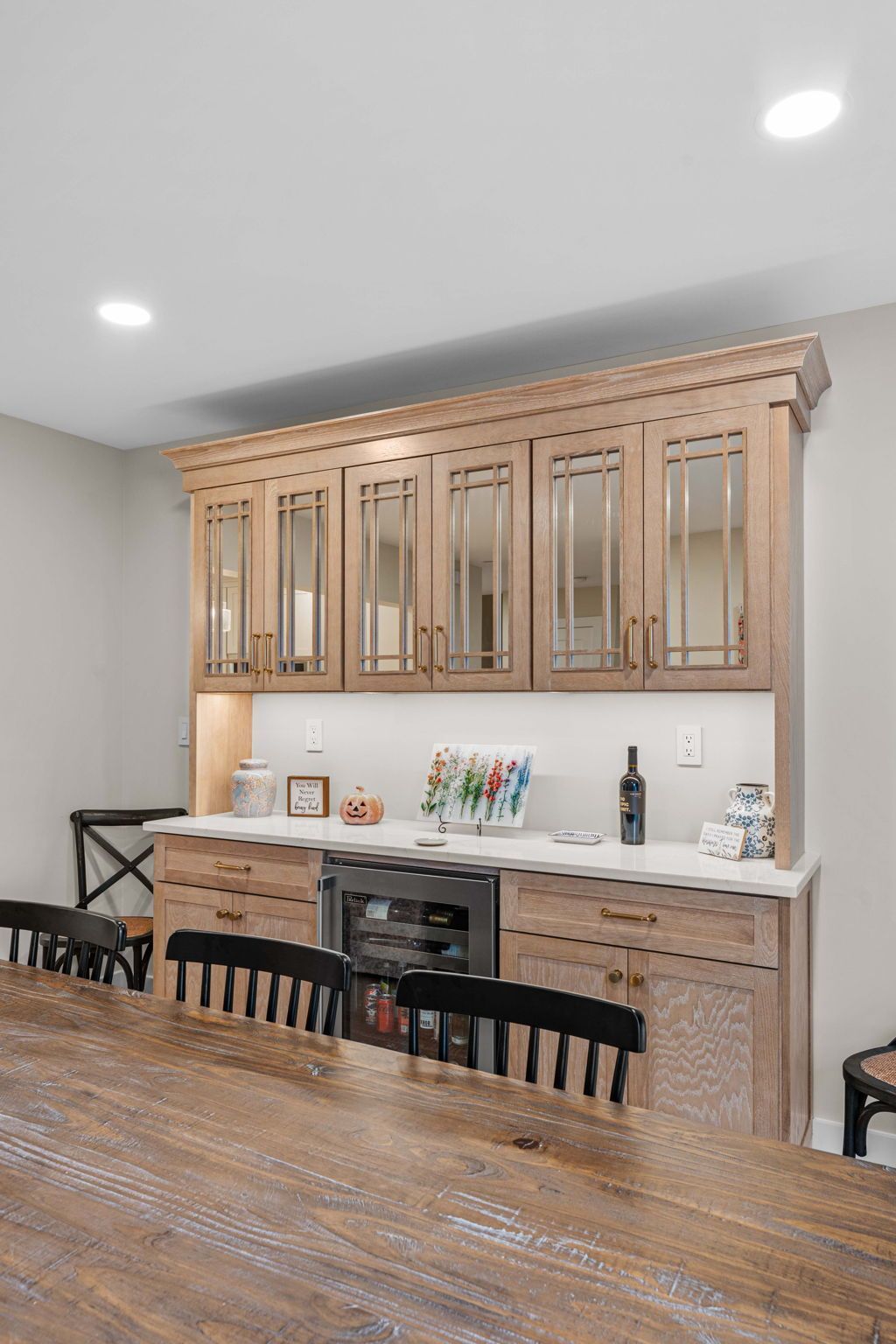 Dining room with rustic wood table and matching hutch, light gray walls, and recessed ceiling lights in Bucks County PA