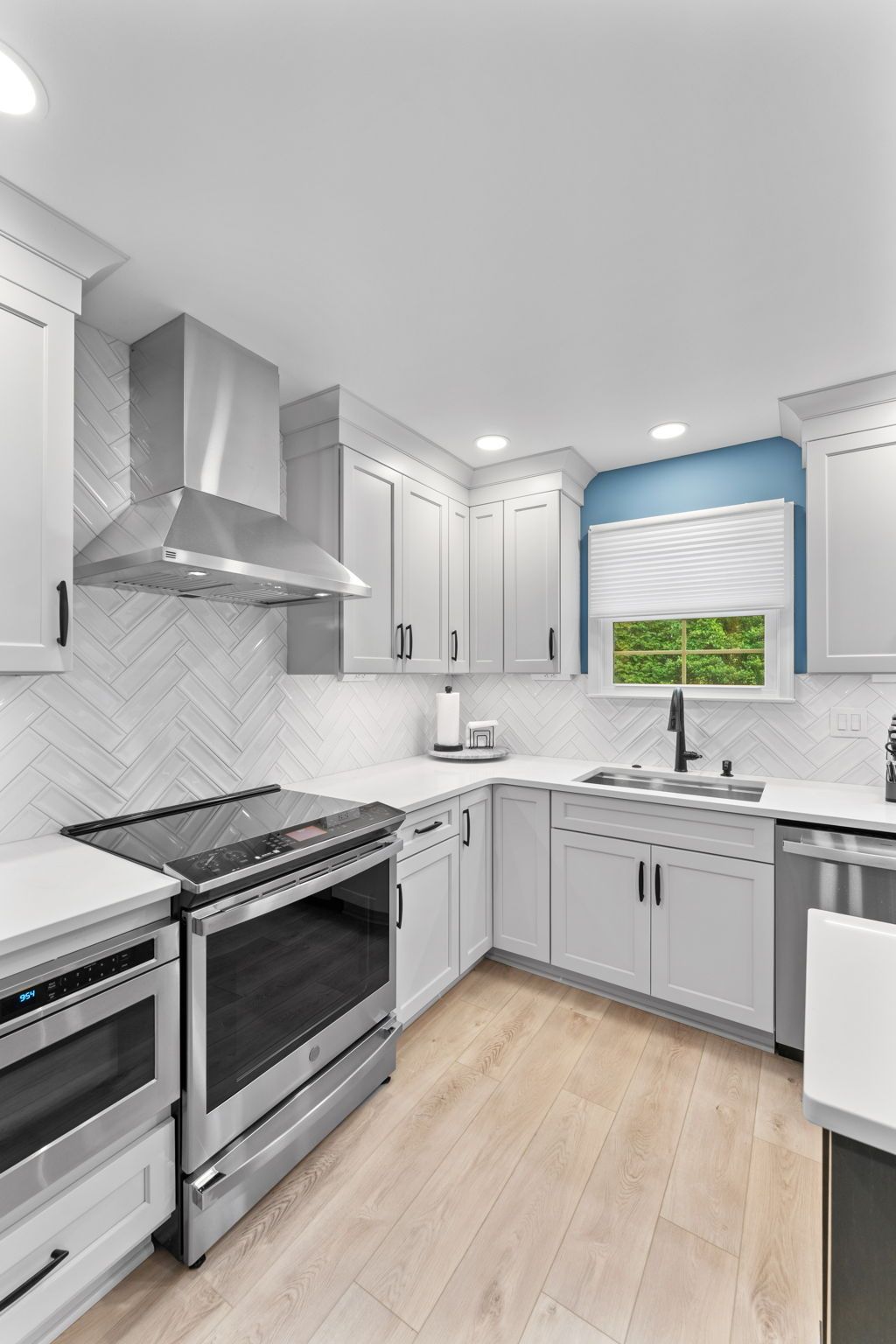 Bright modern kitchen with stainless steel appliances, white cabinets, and a window above the sink. In Bucks County PA