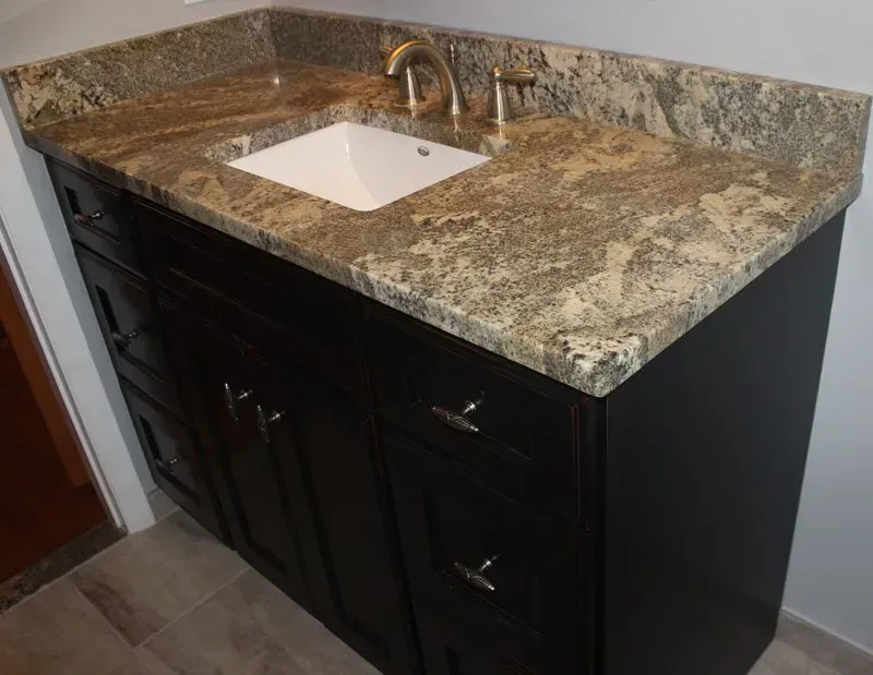 Dark wood bathroom vanity with speckled granite countertop and white sink basin  In Bucks County PA