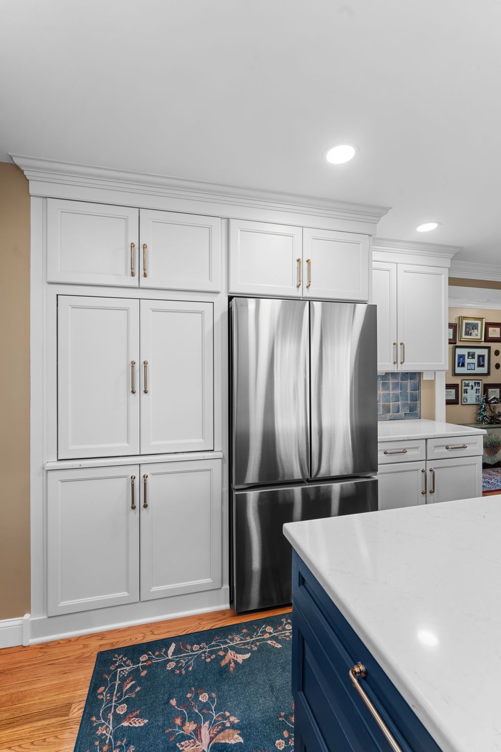 Bright kitchen with white cabinets, stainless steel refrigerator, blue island, and patterned rug  In Bucks County PA