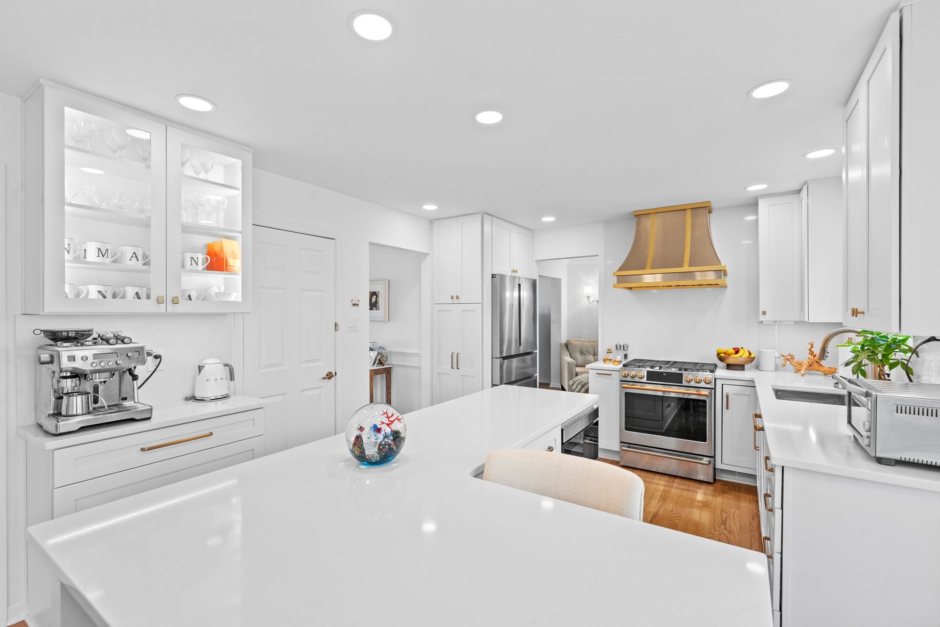 Bright modern kitchen with white cabinets, stainless appliances, and gold range hood In Bucks Country PA