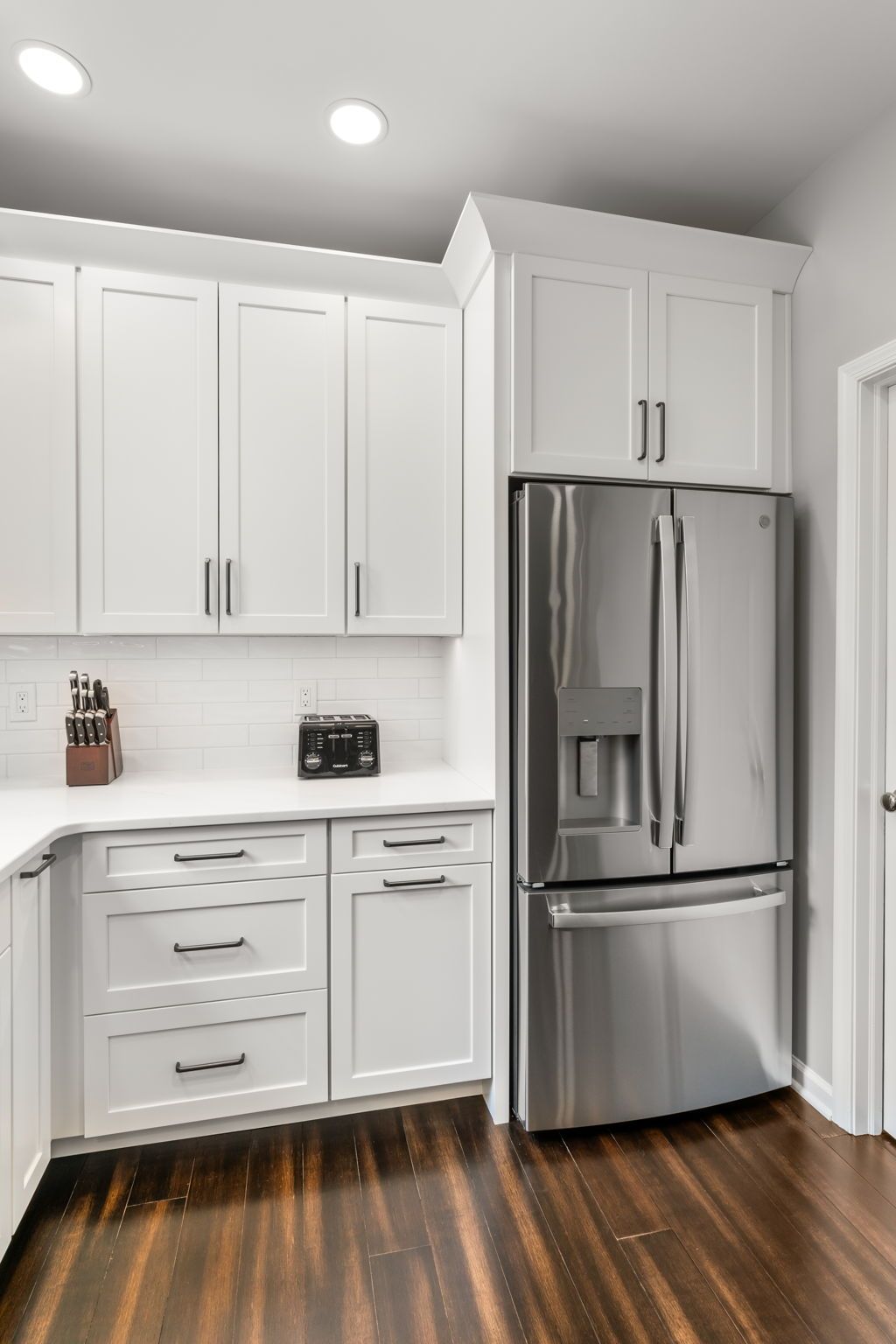 Bright white kitchen with stainless steel refrigerator, cabinets, and dark wood floors  In Bucks County PA