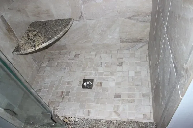 Walk-in shower with glass door, tiled walls, and a corner seat drain  In Bucks County PA