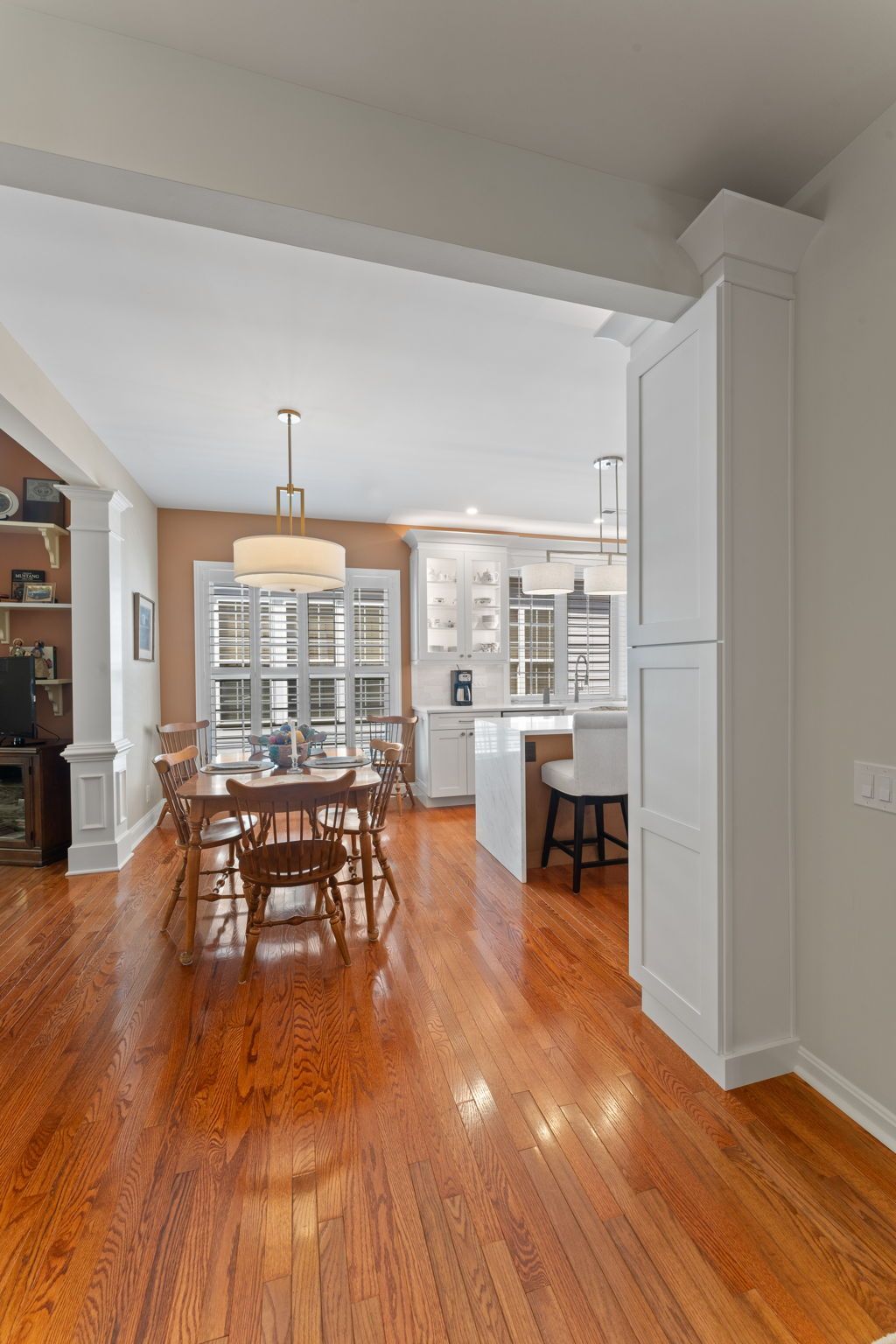 Dining room with wooden table, chairs, and shiny hardwood floors, opening into a bright kitchen In Bucks County PA