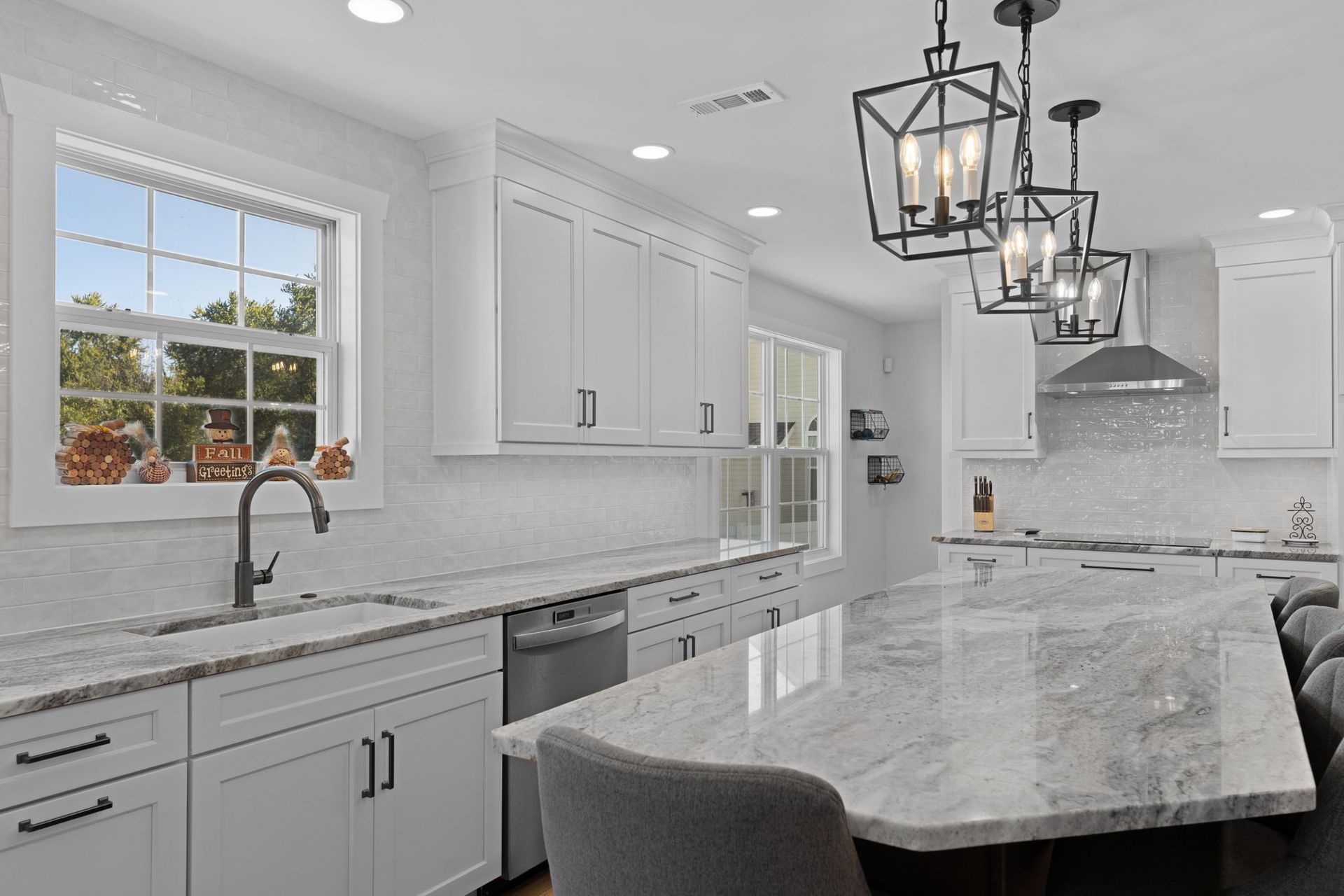 Bright white kitchen with marble island, pendant lights, and large window over the sink  In Bucks County PA