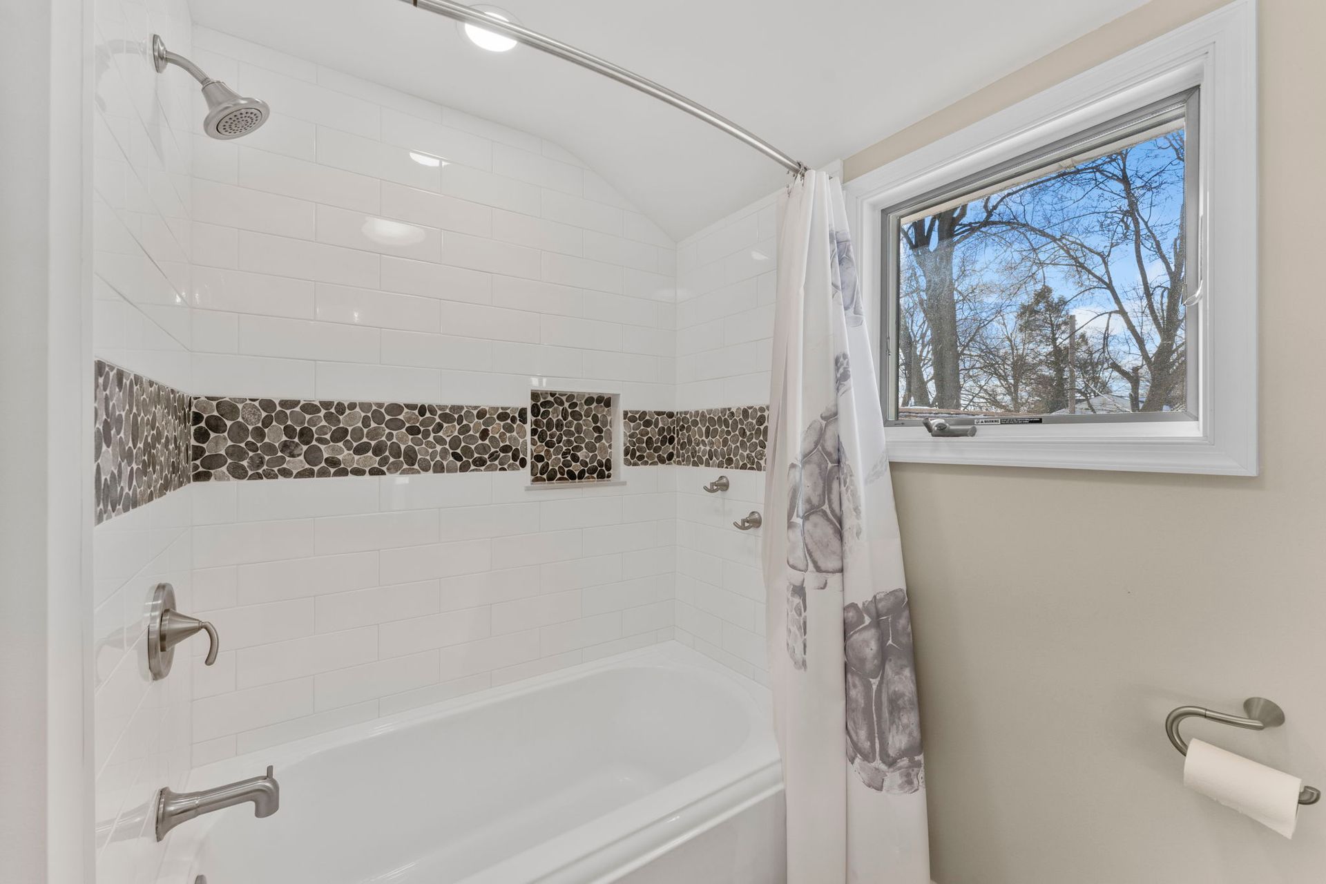 White tiled bathroom shower with mosaic accent strip and a window beside the tub In Bucks County PA