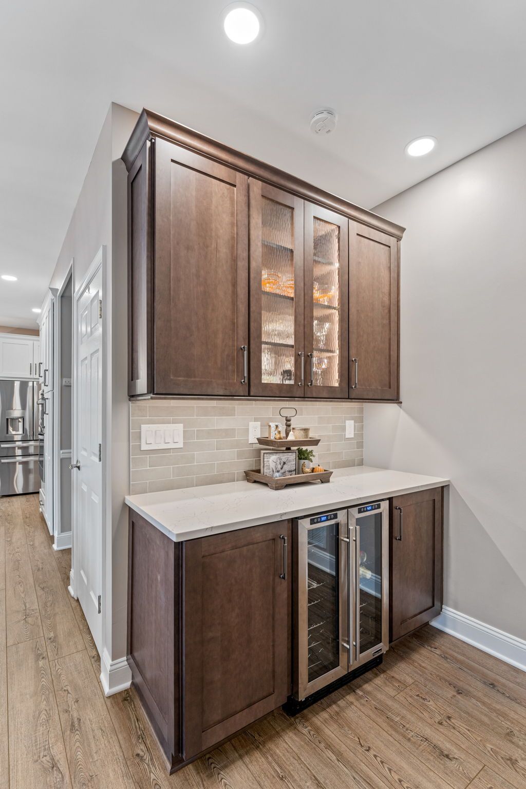 Built-in dark wood cabinet with glass doors and marble countertop in a bright hallway kitchenette  In Bucks County PA