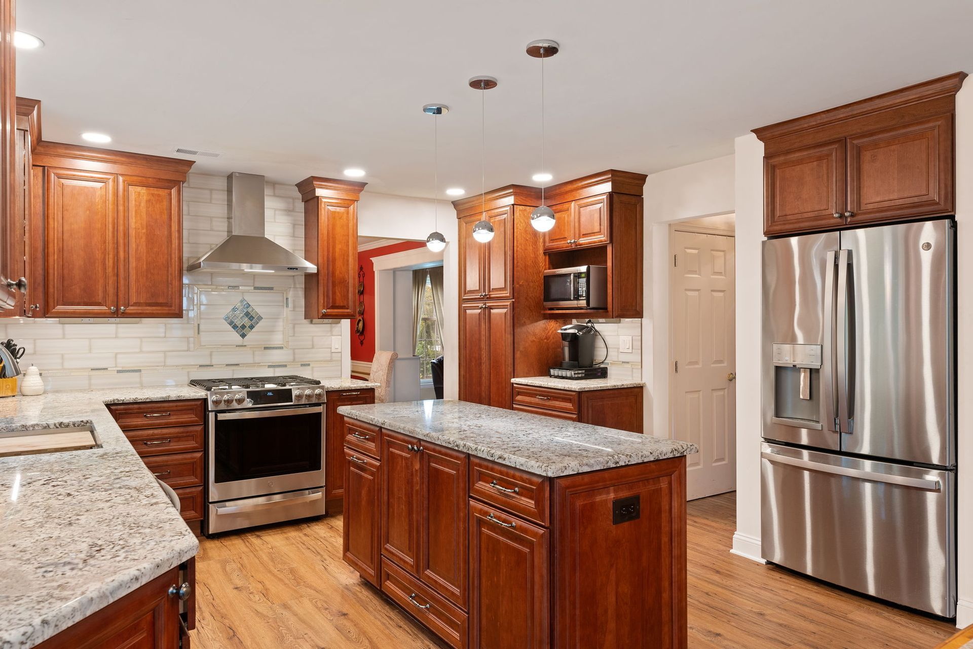 Bright modern kitchen with wood cabinets, granite island, stainless steel appliances, and hardwood floors  In Bucks County PA
