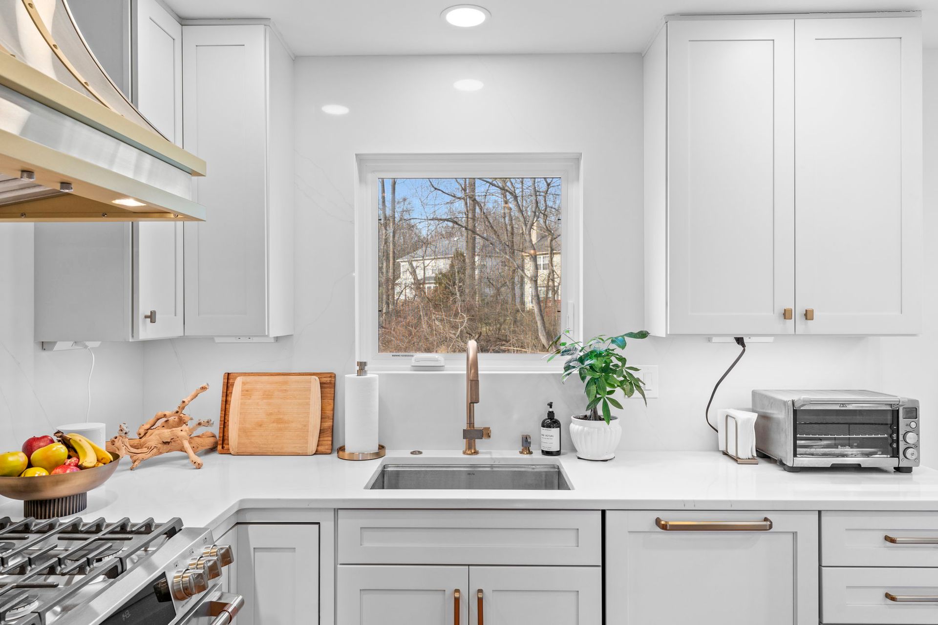 Bright white kitchen with sink, stove, window, and wooden countertops under daylight In Bucks Country PA