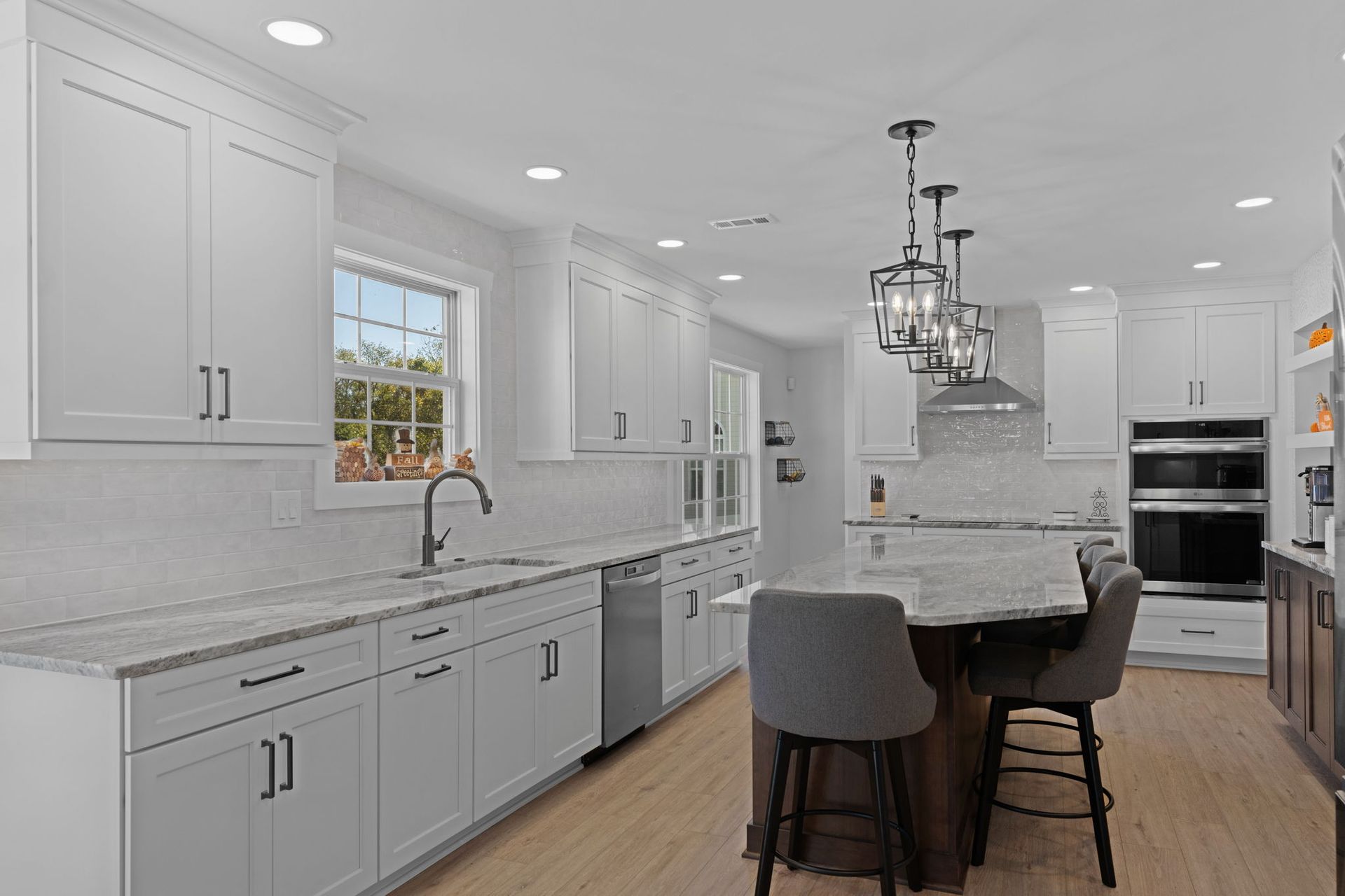 Bright white modern kitchen with island, pendant lights, and bar stools on wood floors In Bucks Country PA
