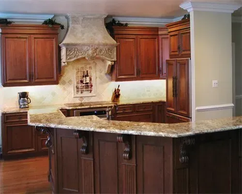 Wooden kitchen with granite island countertop and built-in range hood In Bucks Country PA