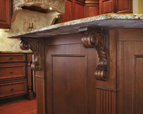 Dark wood kitchen island with ornate carved corbels and granite countertop in a traditional kitchen In Bucks County PA