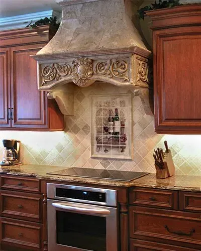 Traditional kitchen with wood cabinets, beige tiled backsplash, and ornate stone range hood above a stainless stove In Bucks County PA