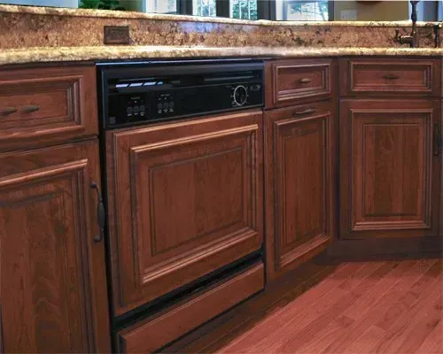 Wood-paneled dishwasher built into dark wood kitchen cabinets under a granite countertop In Bucks County PA