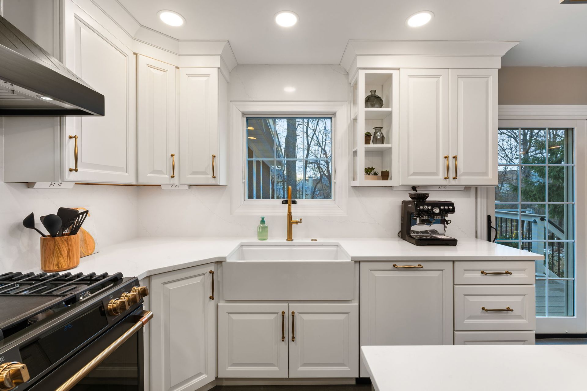 Bright white kitchen with farmhouse sink, black stove, and window above the counter In Bucks Country PA