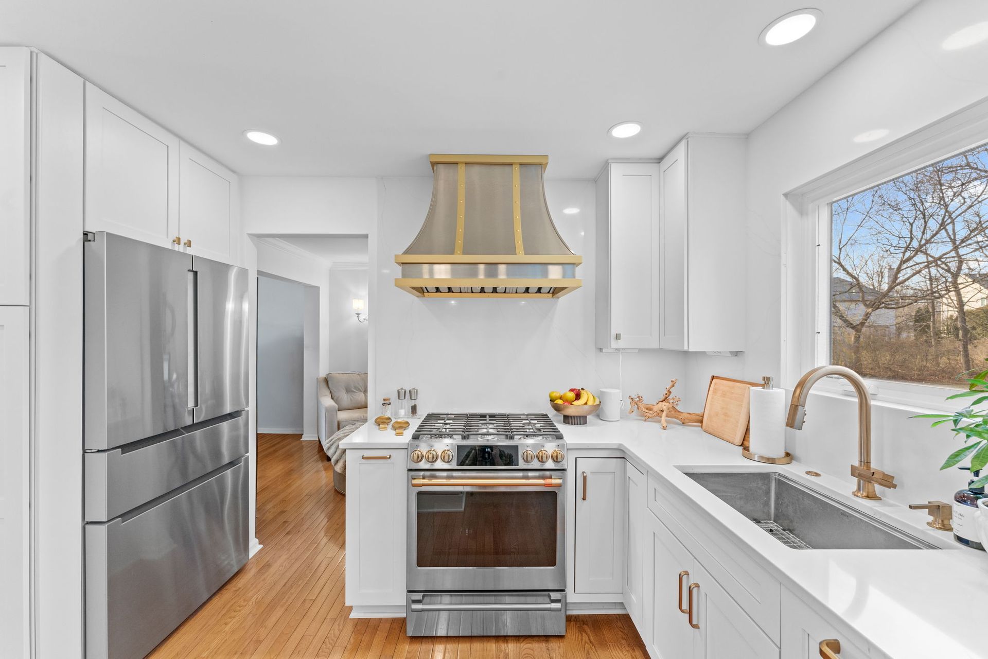 Bright white kitchen with stainless steel appliances, wooden floors, and a window over the sink In Bucks Country PA