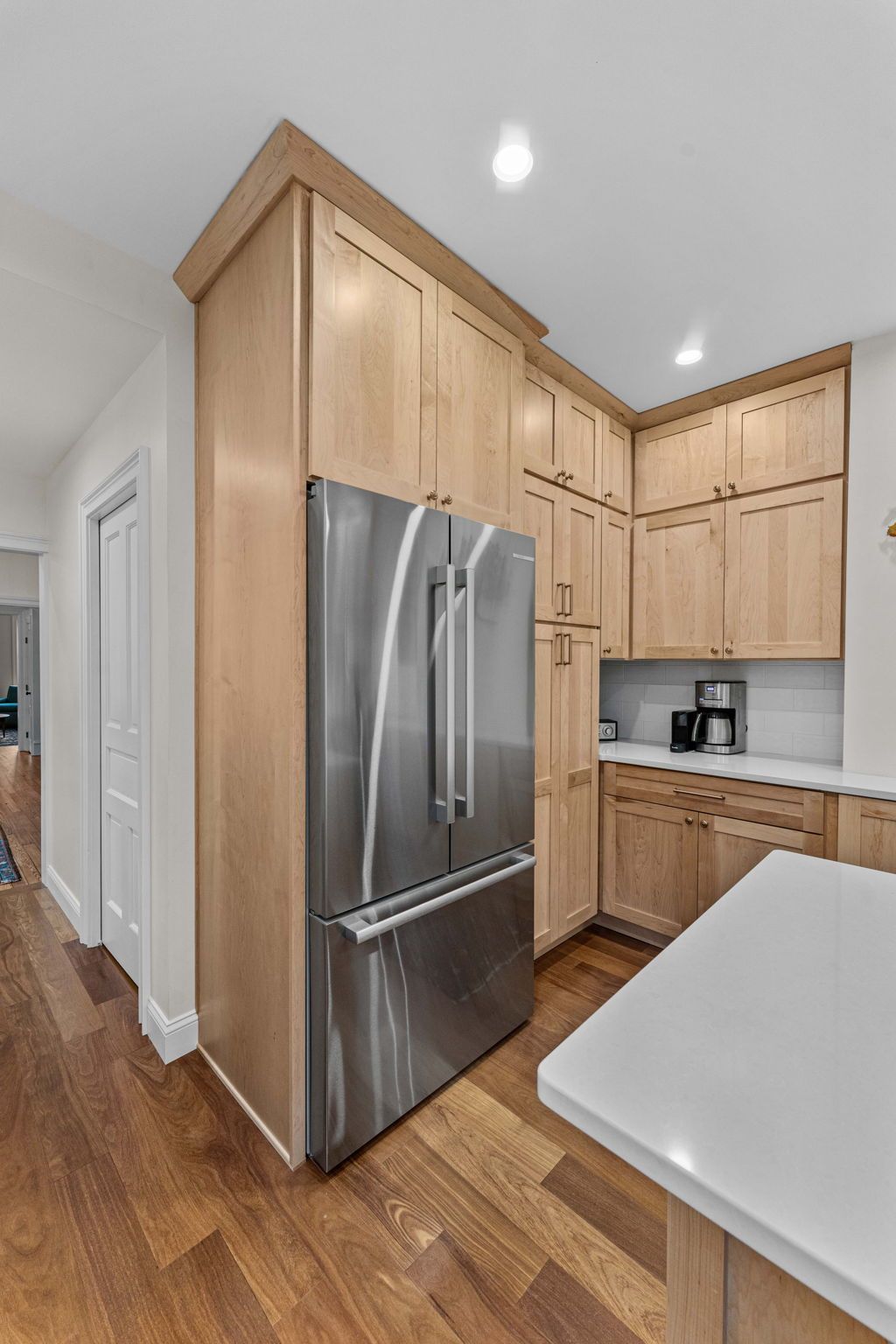 Modern kitchen with stainless steel refrigerator, light wood cabinets, and white countertops In Bucks County PA