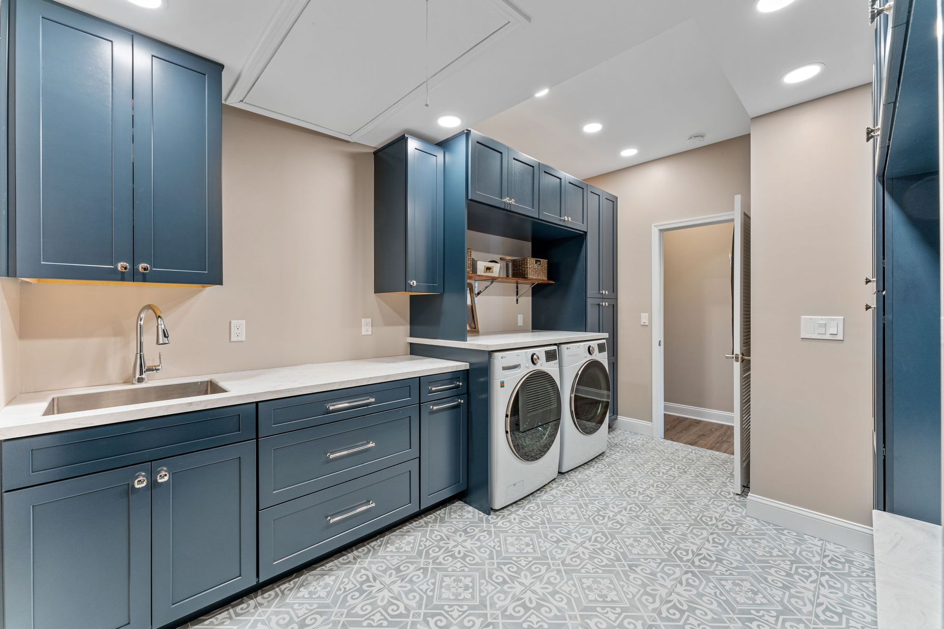 Laundry room with blue cabinets, white countertops, and washer and dryer beside a tiled shower In Bucks County PA