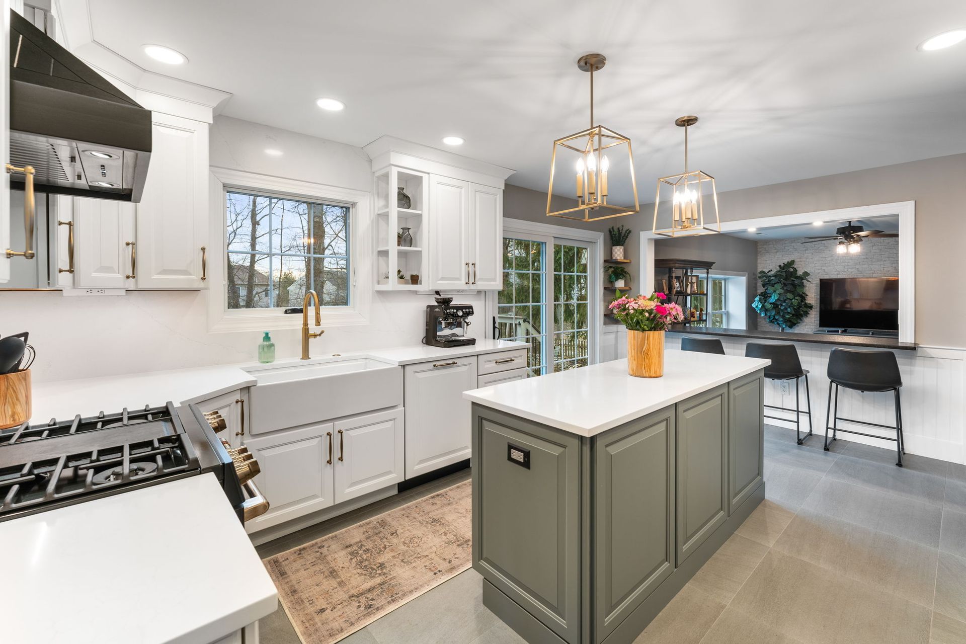Bright modern kitchen with white cabinets, gray island, and pendant lights, open to dining area In Bucks Country PA