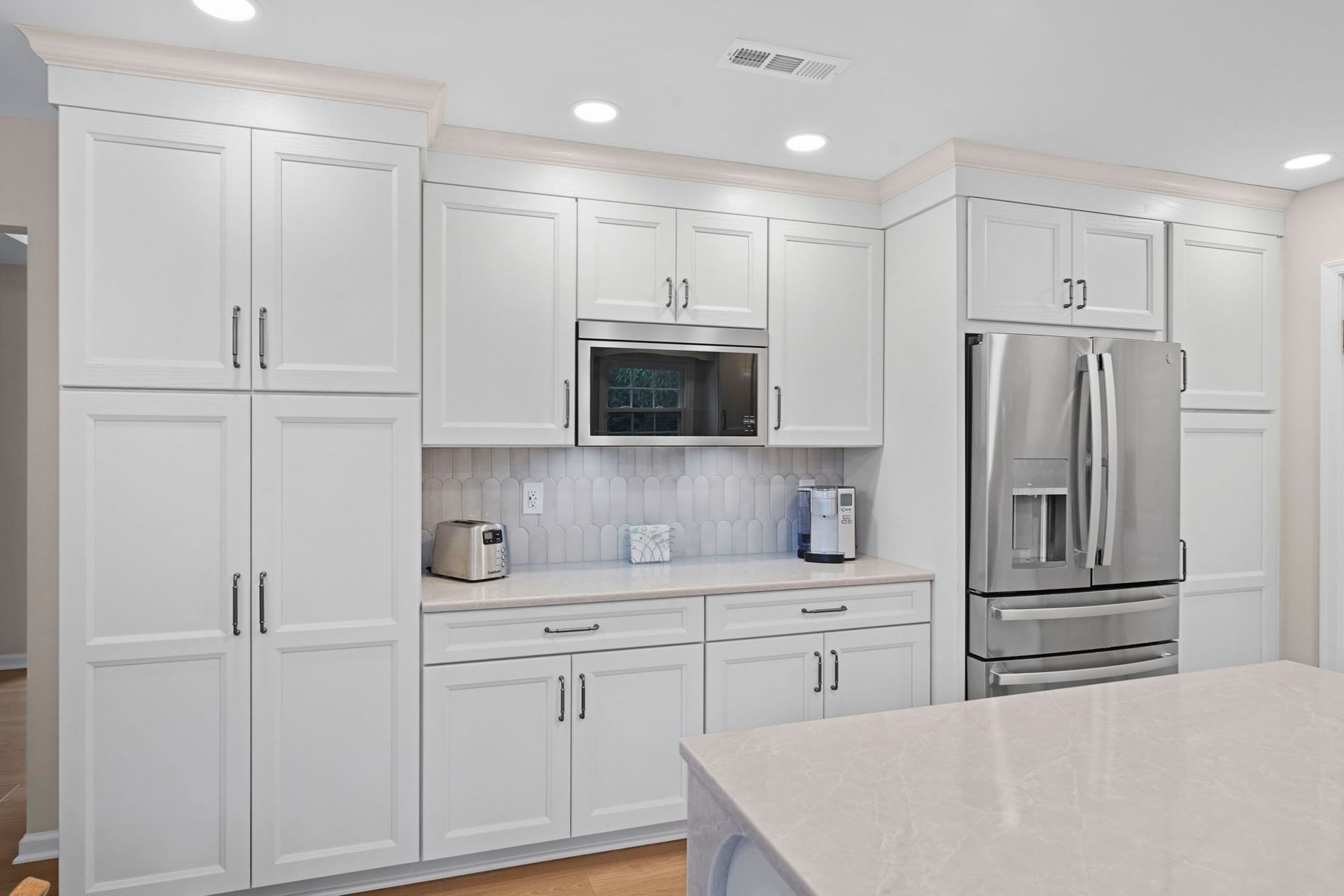 Bright white modern kitchen with stainless steel appliances, cabinets, and a large refrigerator in Bucks County PA