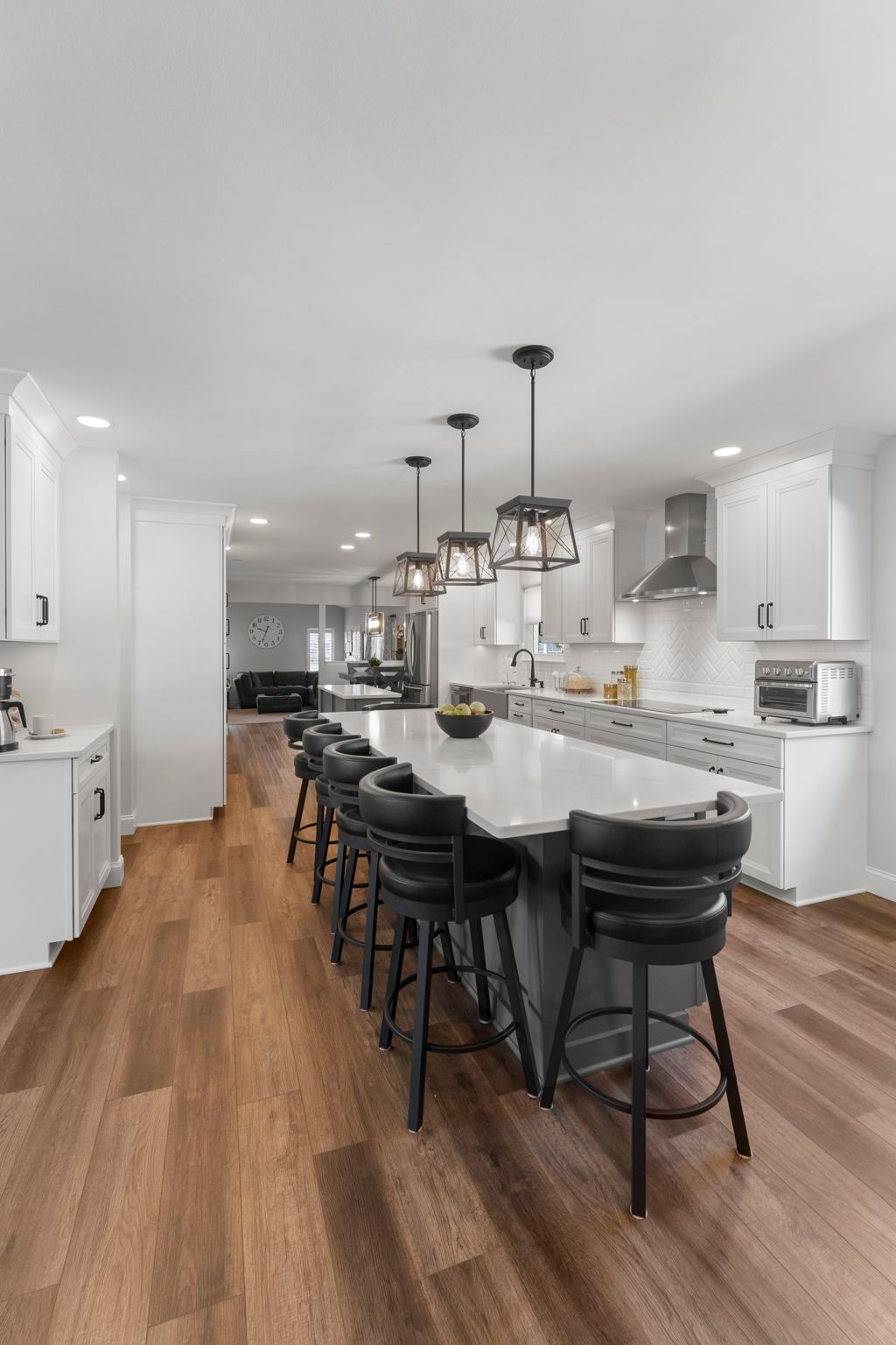 Modern white kitchen with dark island chairs, pendant lights, and wood floors In Bucks County PA