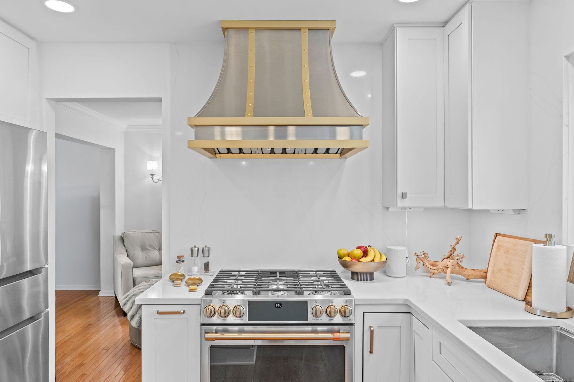 Bright modern kitchen with white cabinets, stainless stove, and gold range hood In Bucks Country PA
