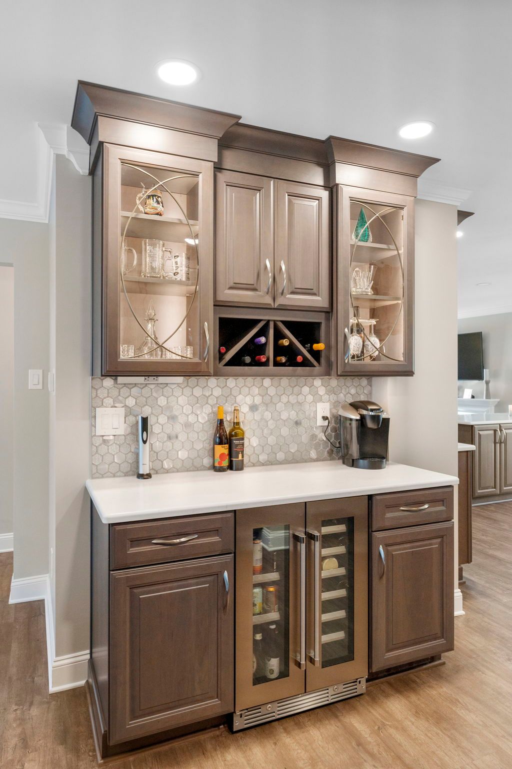 Kitchen wet bar with dark wood cabinets, wine cooler, granite countertop, and glass-front display shelves In Bucks Country PA