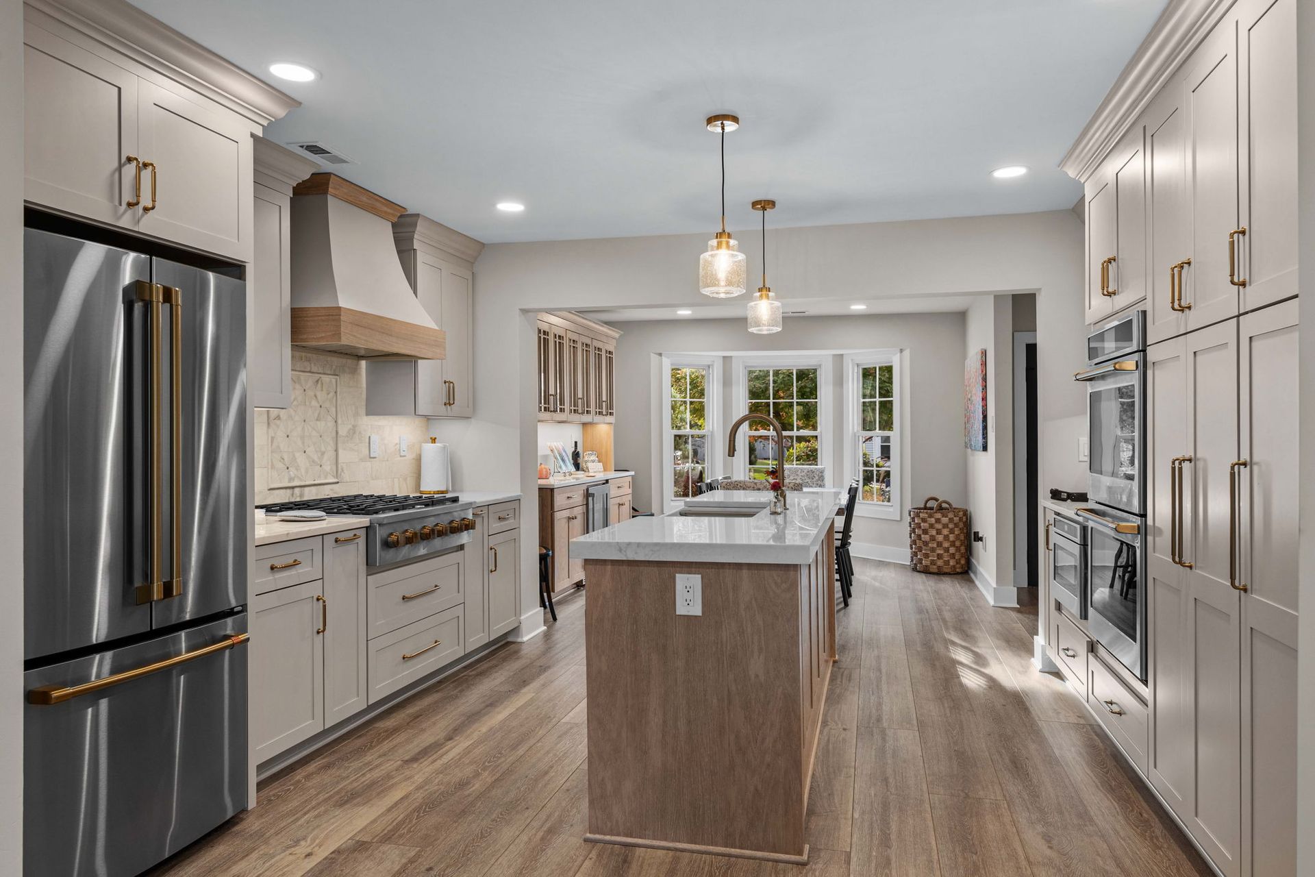 Bright modern kitchen with stainless appliances, white cabinets, island, and wood floors in Bucks County PA