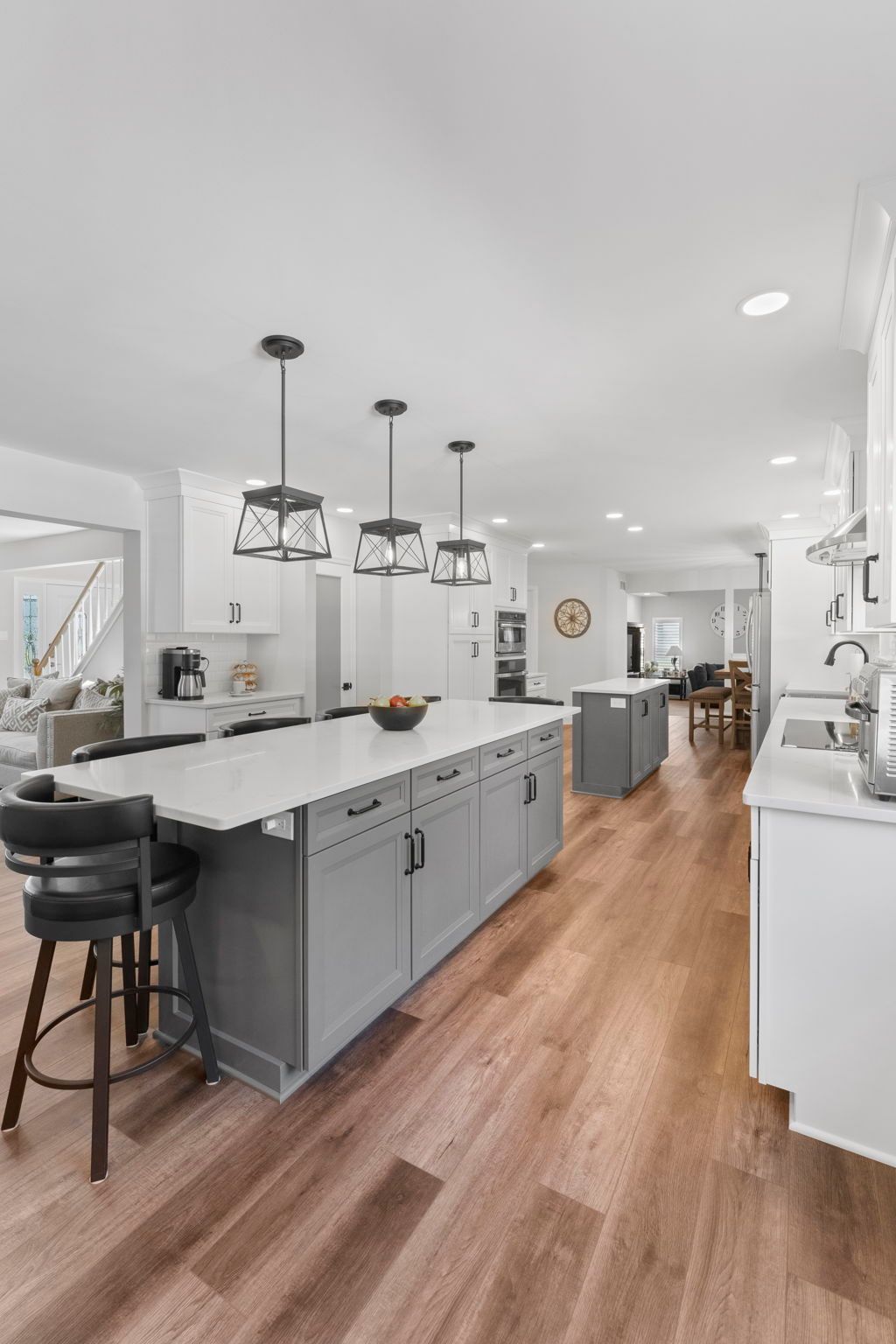Bright modern kitchen with gray island, pendant lights, white cabinets, and wood floors In Bucks County PA