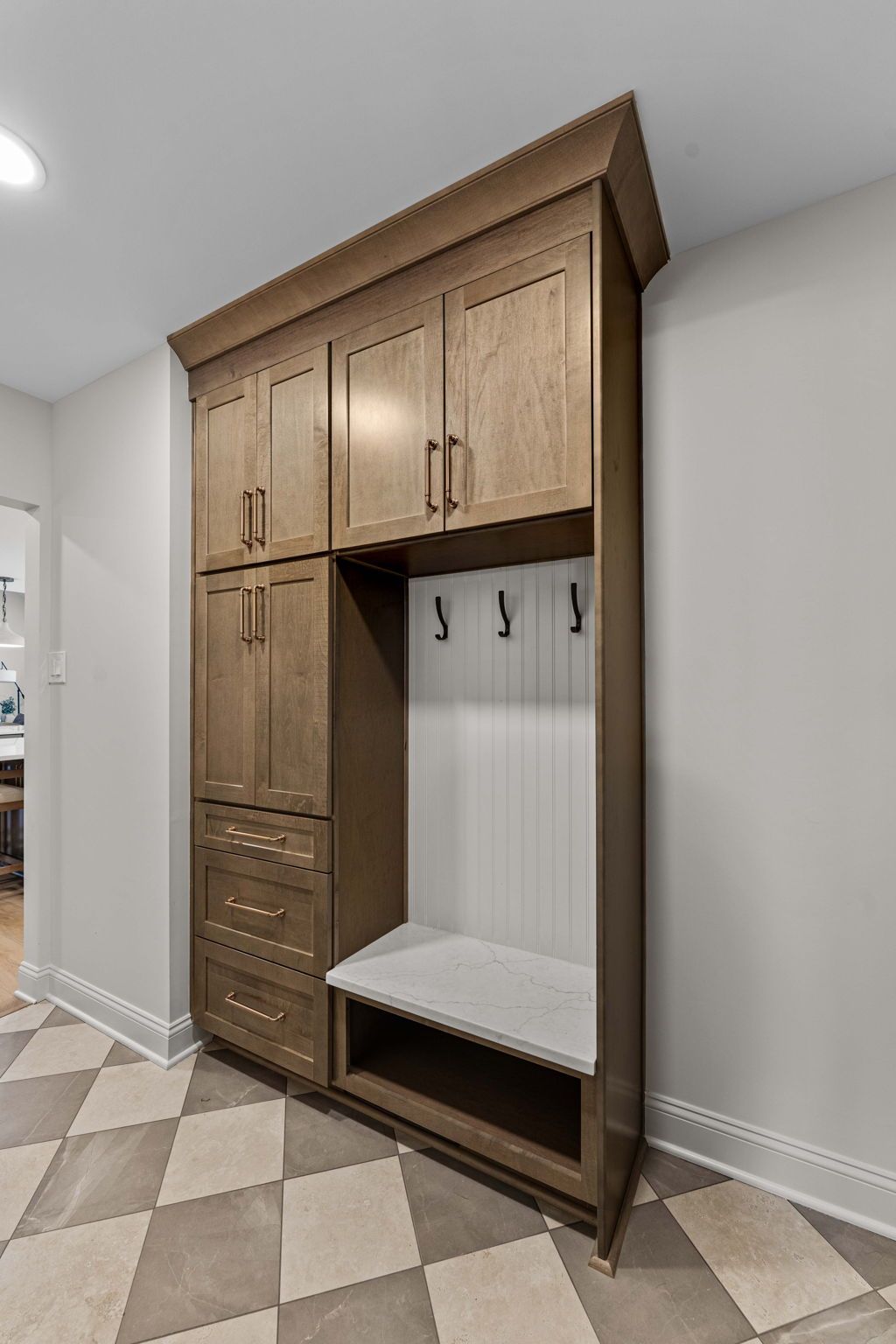 Wooden mudroom cabinet with bench, drawers, and coat hooks against a light wall in Bucks County PA