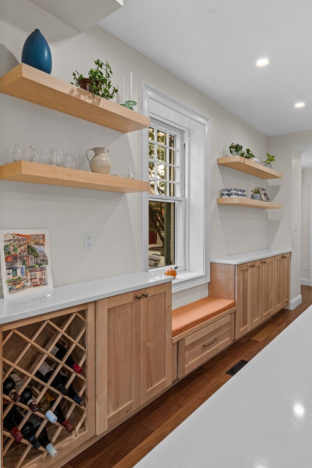 Built-in hallway storage with wood cabinets, wine rack, shelves, and a bench by a window In Bucks County PA