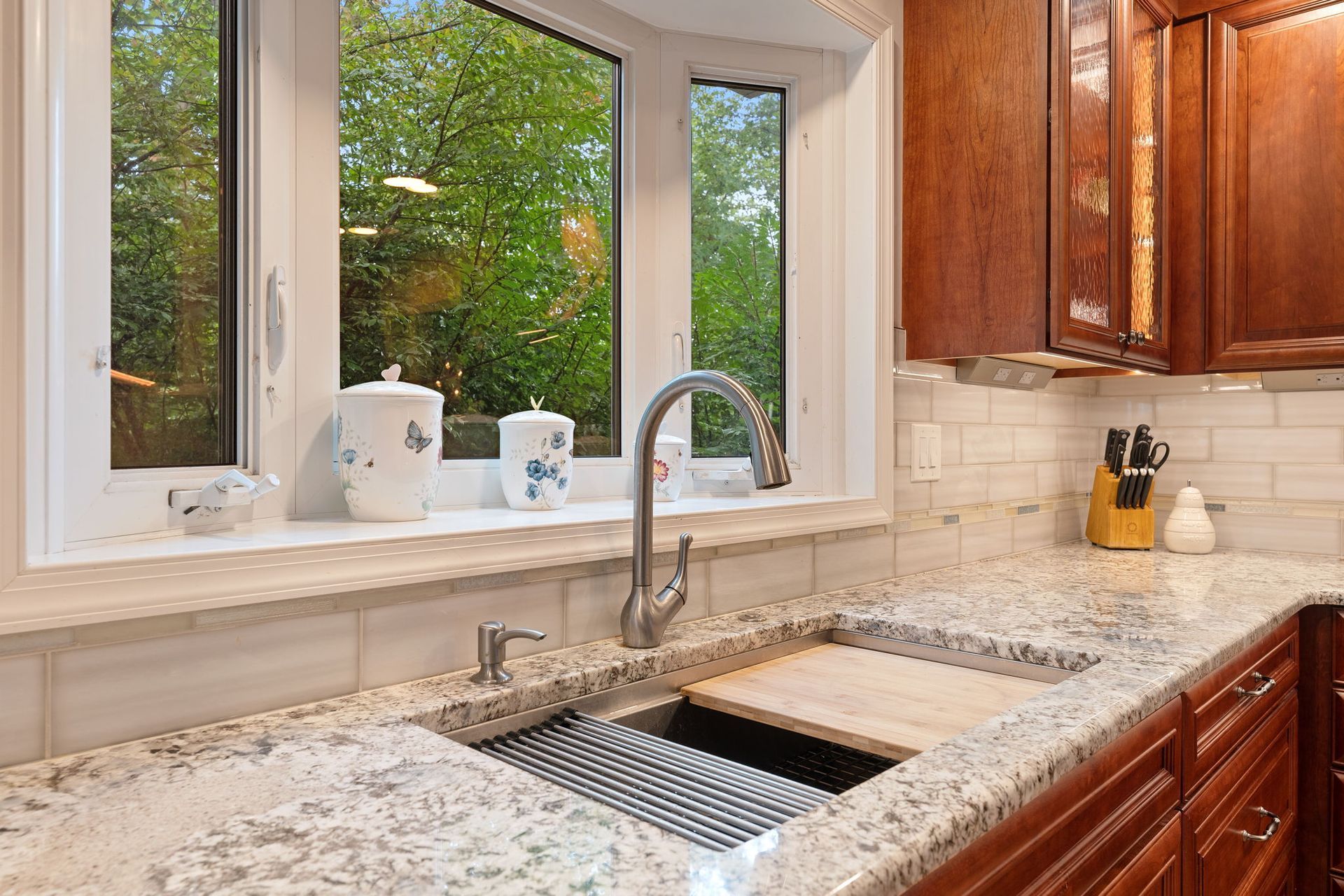 Kitchen sink by a window with granite countertop, stainless faucet, and wood cabinets  In Bucks County PA