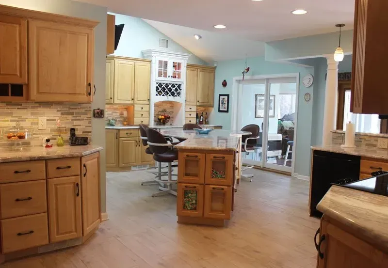 Bright kitchen with wood cabinets, island cart, and open view into a dining room and hallway In Bucks County PA