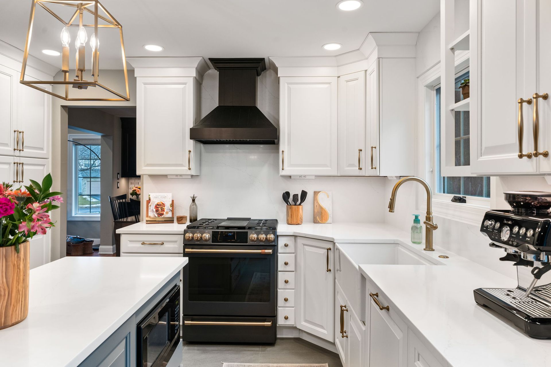 Bright white modern kitchen with black stove, gold pendant lights, and a large island In Bucks Country PA