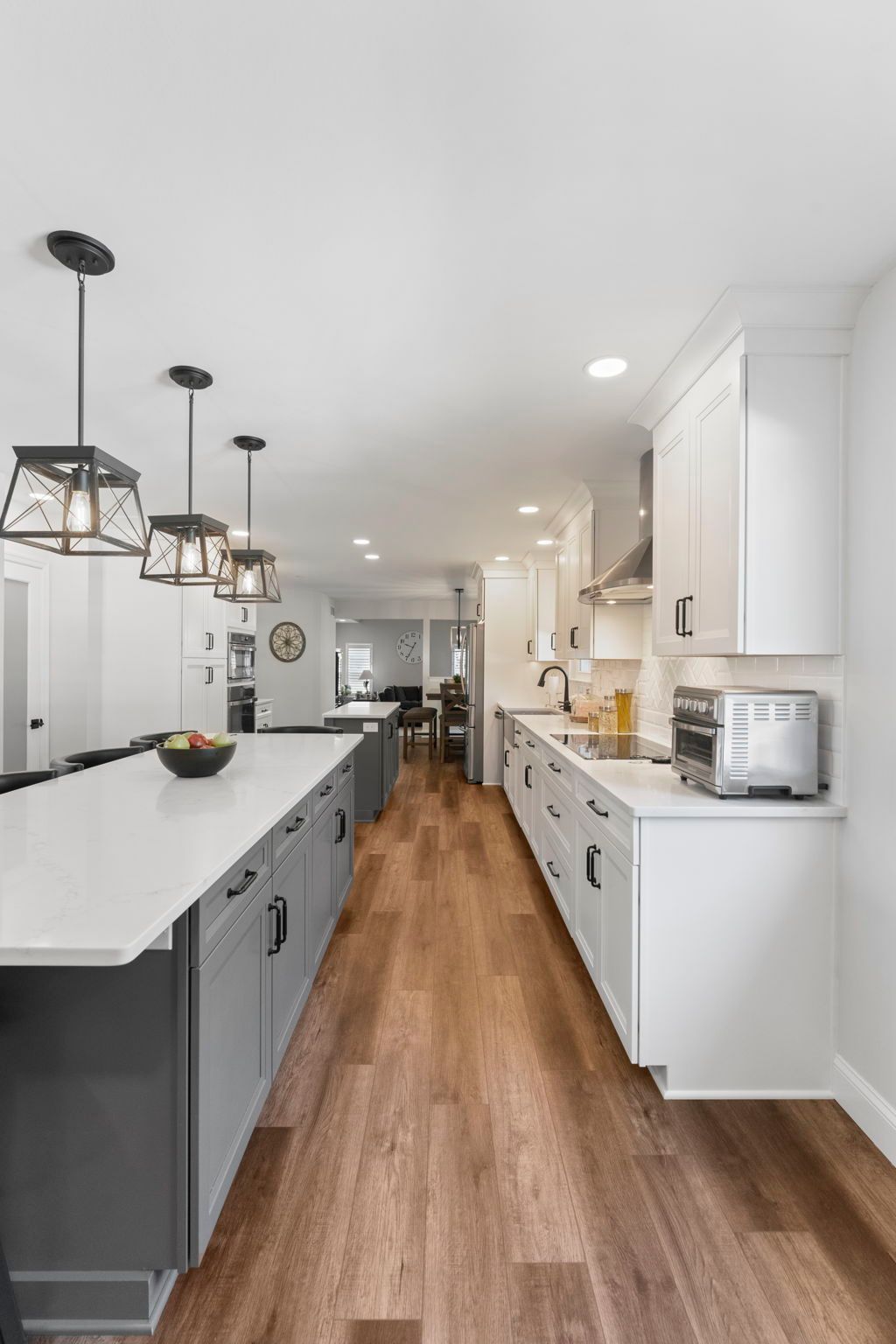 Modern white kitchen with gray island, wood floors, and black pendant lights In Bucks County PA
